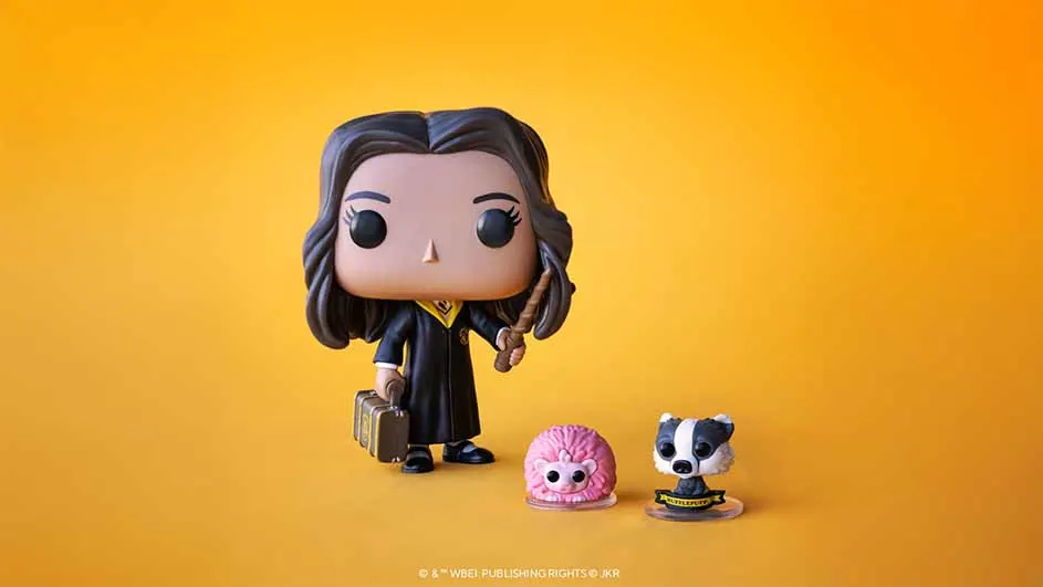 Figurine d'une personne tenant une baguette et une valise, avec un niffleur rose et un blaireau sur un fond orange.