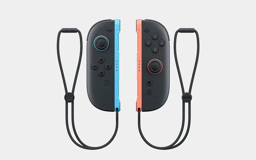 Twee Nintendo Switch Joy-Con-controllers, één blauw en één rood, liggen naast elkaar met polsbandjes eraan.