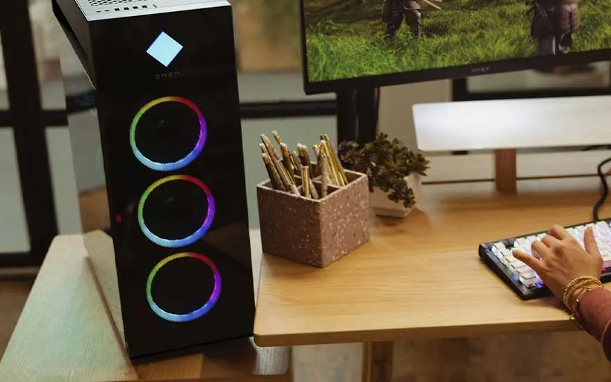 Een bureau met twee monitoren met een kleurverloop, een toetsenbord, een muis en een computer met verlichting.