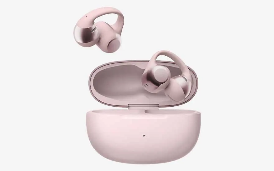 Twee roze draadloze oordopjes met oorhaakjes zweven boven een open laadcase op een strakke witte achtergrond.