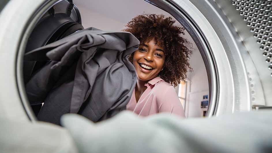 Vue de l'intérieur d'un sèche-linge avec des vêtements gris. L'intérieur du sèche-linge est métallique.