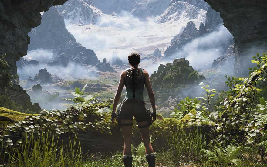 Lara se tient à l’entrée d’une grotte verdoyante, contemplant une vallée brumeuse, des ruines et de hautes montagnes enneigées.