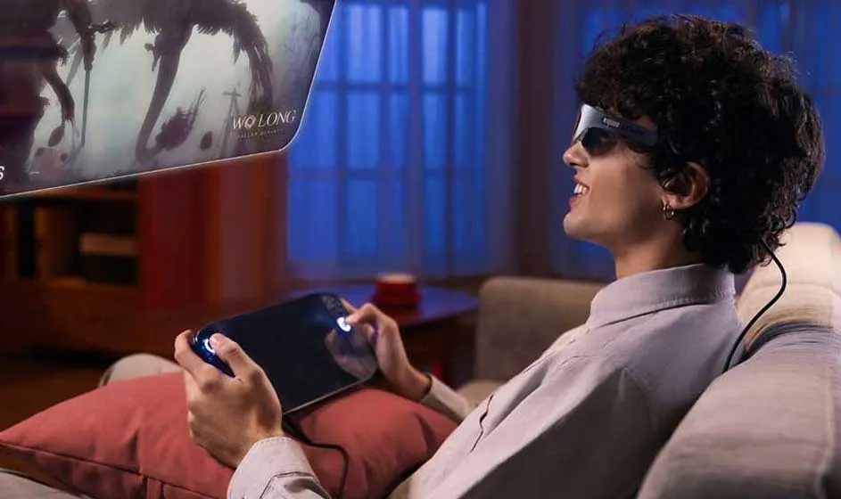 Man zit op een bank met een tablet en een bril die een scherm projecteert met het spel Wo Long.