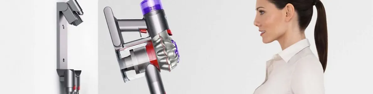 Un aspirateur Dyson sans fil argent é avec une station de charge murale sur un fond blanc uni.