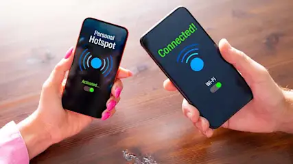 Twee telefoons: één met "Personal Hotspot" actief, de andere "Connected!" via wifi, beide met groene statuslampjes op een houten tafel.