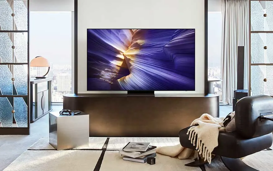 Een stijlvolle woonkamer met moderne meubels en een grote tv die abstracte, paarse vormen toont op het scherm.
