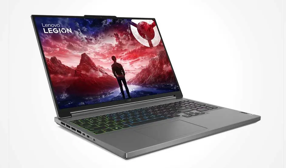 A grey Lenovo Legion laptop sits at an angle on a white background; a rainbow-lit keyboard and a mountain scene with a figure fill the screen.