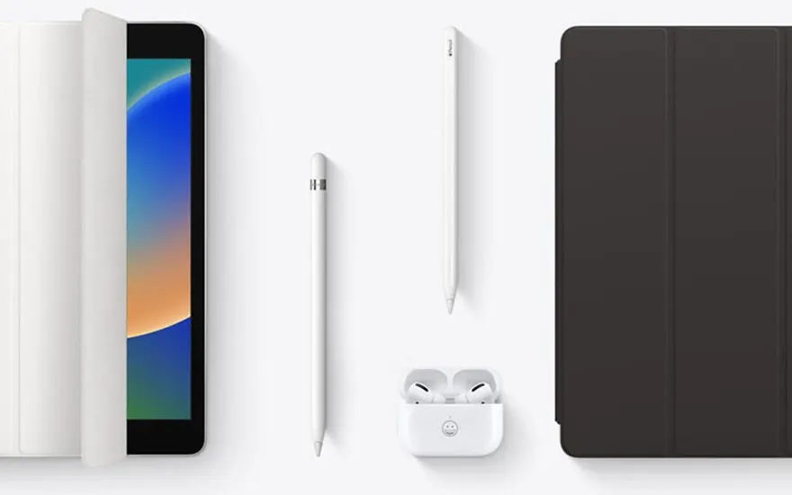 Un iPad avec une couverture ouverte, deux stylets, des oreillettes dans un étui et une couverture d'iPad marron.