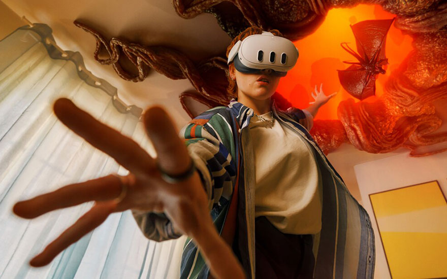 Een VR-bril en uitgestrekte hand in een kamer met gestreepte muren en een oranje achtergrond.