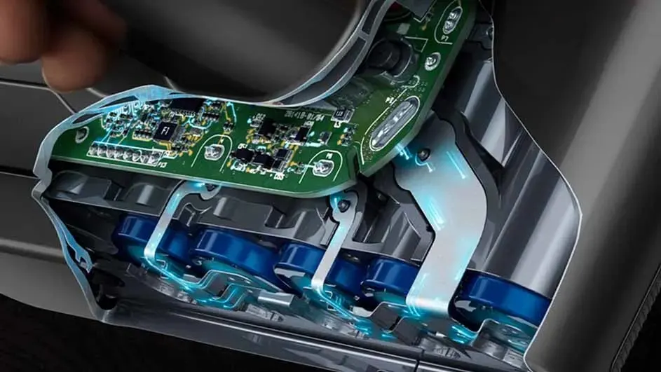 Een close-up toont een groene printplaat en blauwe batterijen in een grijze, metalen behuizing met blauwe accentverlichting.