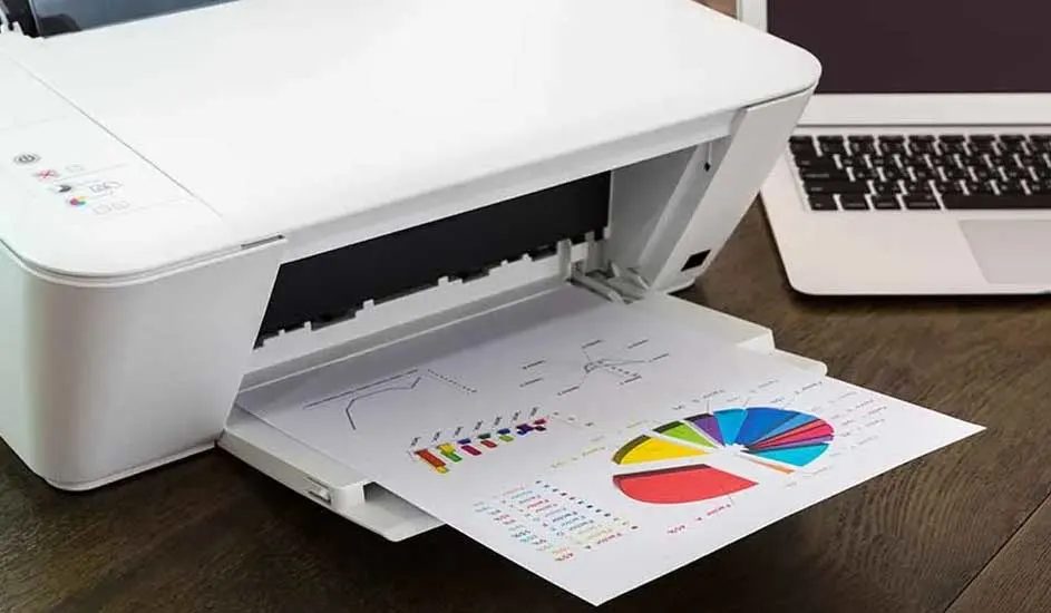 Une imprimante blanche imprime un graphique circulaire coloré sur du papier. Un ordinateur portable est visible en arrière-plan.
