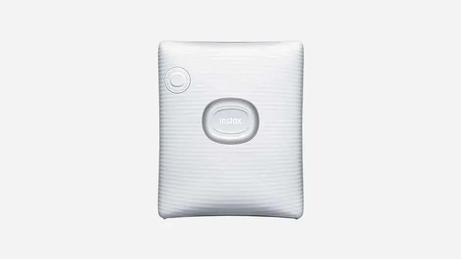 A white, rectangular Instax printer stands centered against a bright background. It features a power button and the Instax logo.