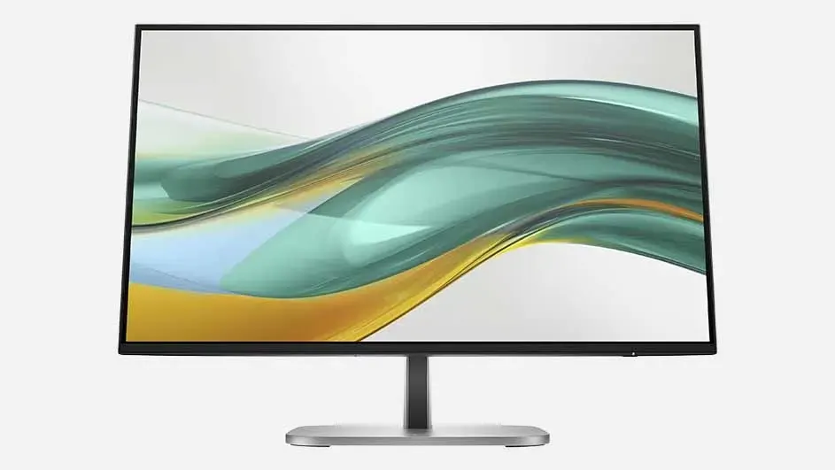 Monitor with thin black bezel on silver stand, displaying abstract flowing wave patterns in green and yellow hues on the screen.