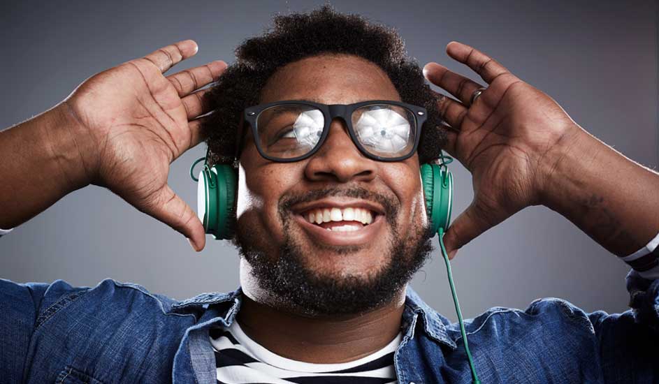 A person wearing green headphones holds both hands near their head, dressed in a denim shirt and a striped T-shirt.