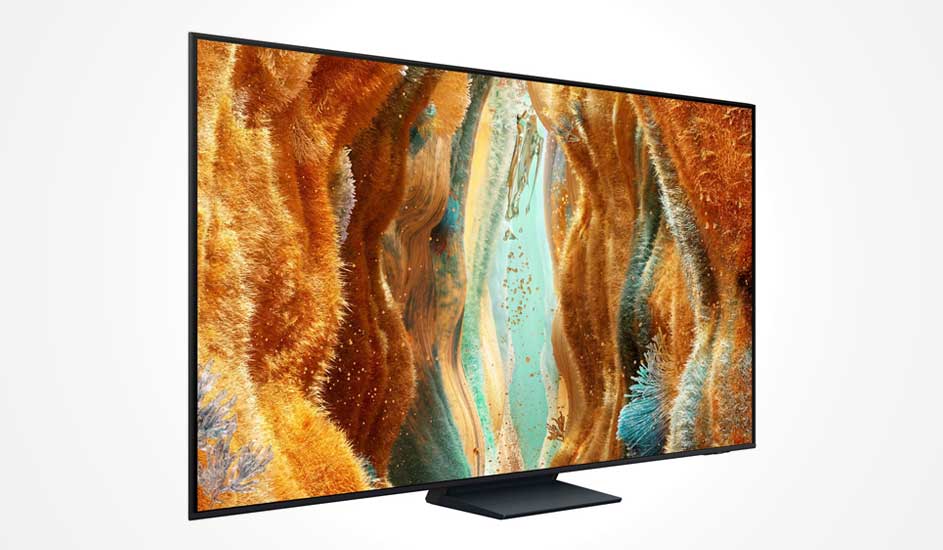 Een Samsung televisie met dun zwart frame staat op een brede voet en toont een abstract beeld met oranje, goud en blauwe tinten op het scherm.