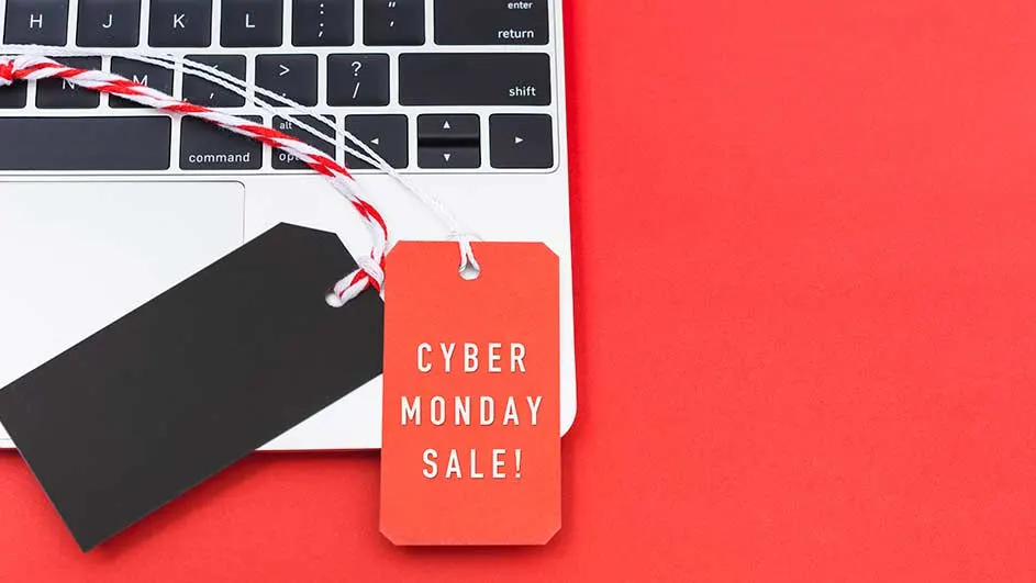 Des étiquettes rouges et noires affichant "Cyber Monday Sale !" posées sur un ordinateur portable sur un fond rouge uni.