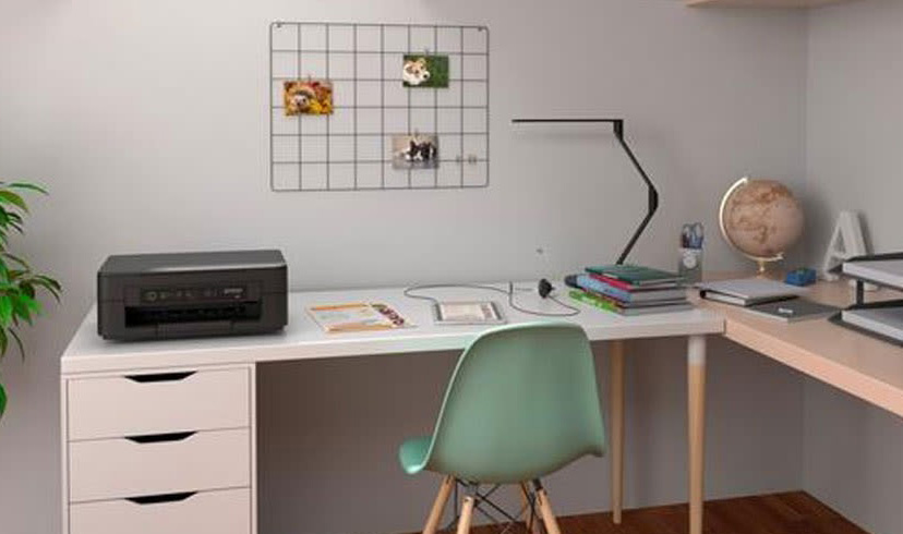 Bureau blanc avec imprimante noire, chaise verte, lampe et globe terrestre dans une pièce.