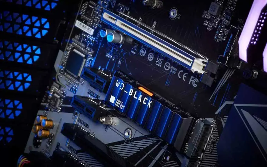 Close-up van een moederbord met blauwe LED-verlichting en een WD_BLACK SSD, met diverse elektronische componenten zichtbaar.