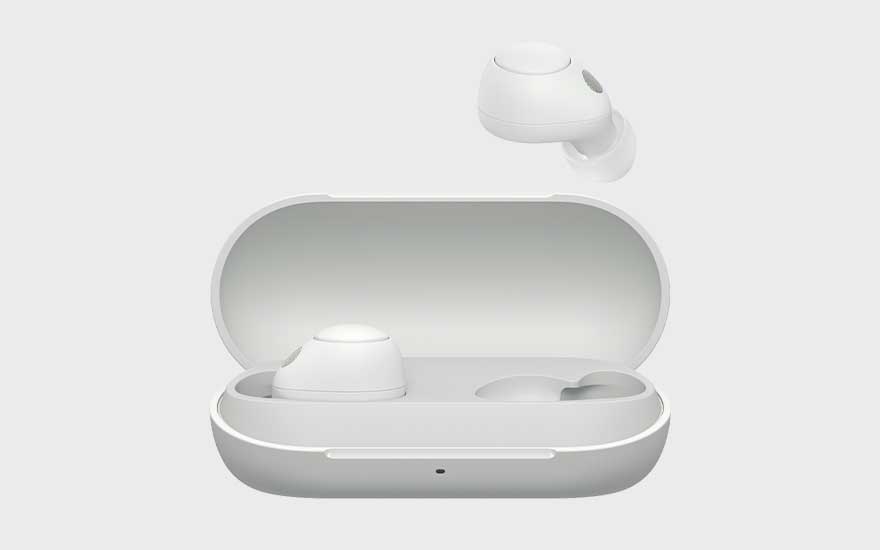 Écouteurs blancs entièrement sans fil posés dans un boîtier de charge ouvert, avec un écouteur flottant au-dessus.