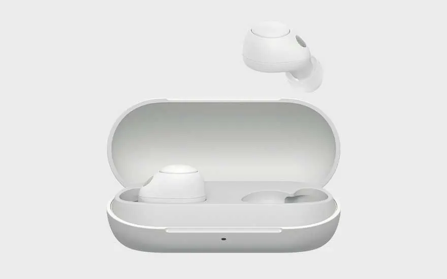 Witte volledig draadloze oordopjes liggen in een open oplaadcase, één oordop zweeft erboven tegen een neutrale achtergrond.