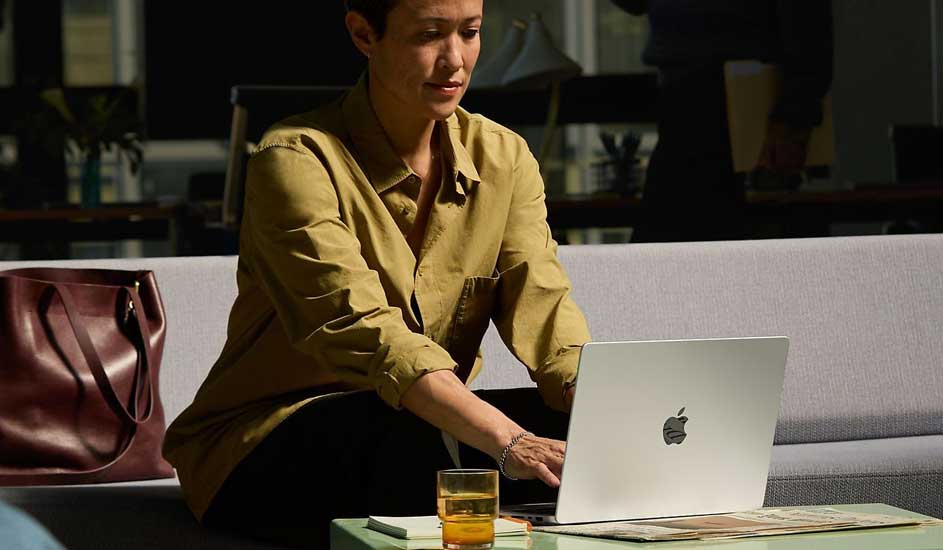 Laptop op tafel met drankje, notitieboekje en handtas op de bank.