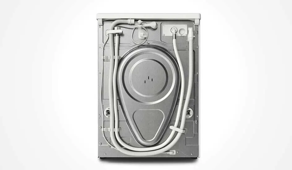 Vue arrière d'une machine à laver blanche avec des tuyaux et un panneau métallique.