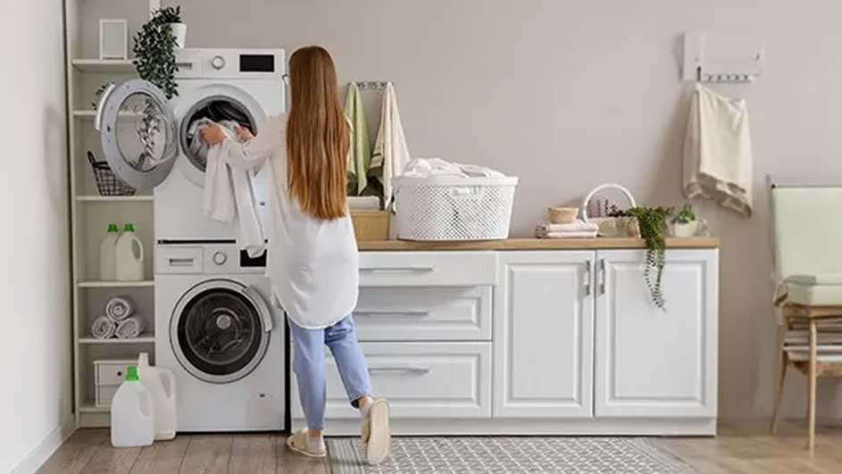 Buanderie avec lave-linge blanc, armoires, panier à linge et produits de nettoyage.