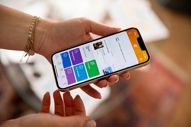 Hand houdt een smartphone vast met de HP Smart-app in beeld.
