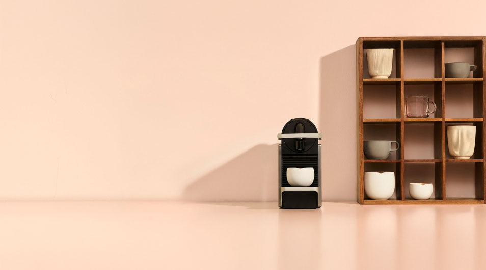 Coin café minimaliste avec une machine compacte et des tasses dans une étagère à cases en bois.
