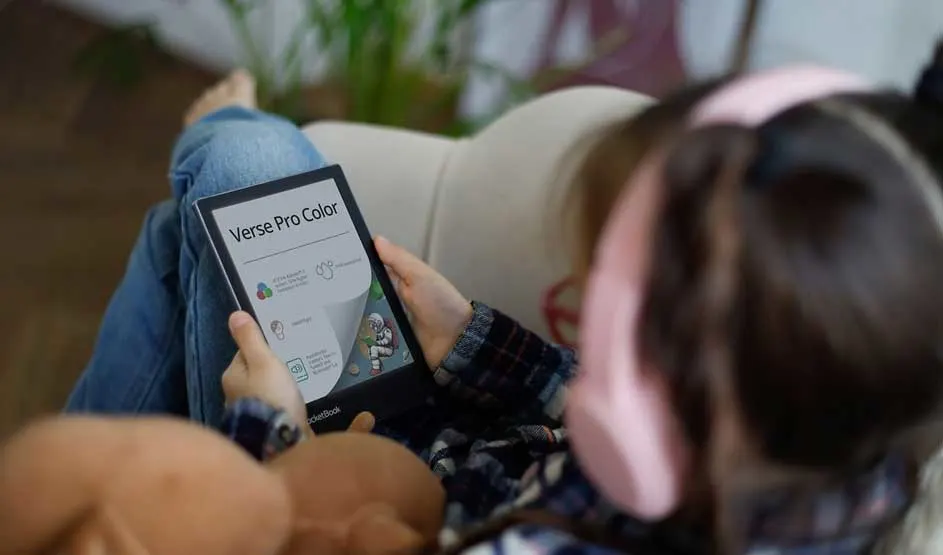 Une personne tient une liseuse affichant "Verse Pro Color". Plantes et décoration d'intérieur visibles en arrière-plan. Atmosphère chaleureuse et rustique axée sur la lecture numérique.