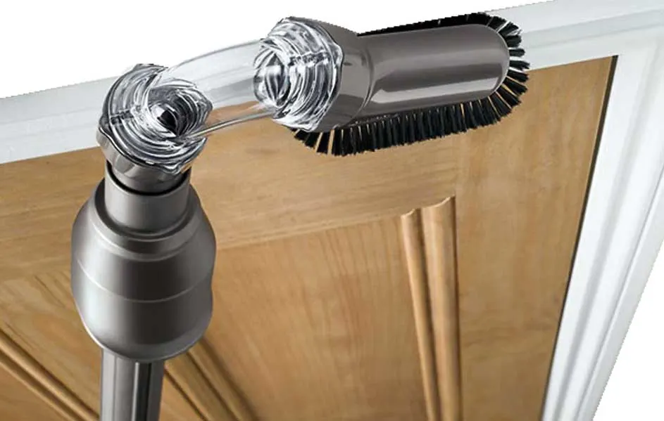 Een stofzuigerborstel met doorzichtige buis raakt een houten deur. De deur heeft een witte omlijsting.