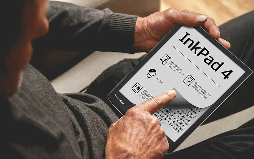 Un homme tient une liseuse InkPad 4. L'écran affiche des informations et du texte. Il est assis sur un canapé gris.