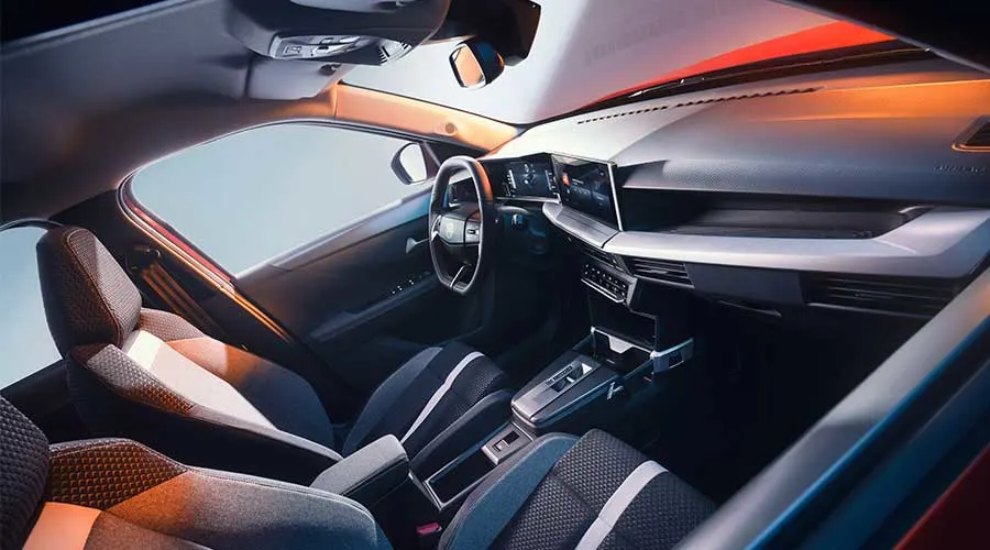 Intérieur moderne d’une voiture avec cockpit numérique, deux sièges avant et console centrale avec boîte automatique.