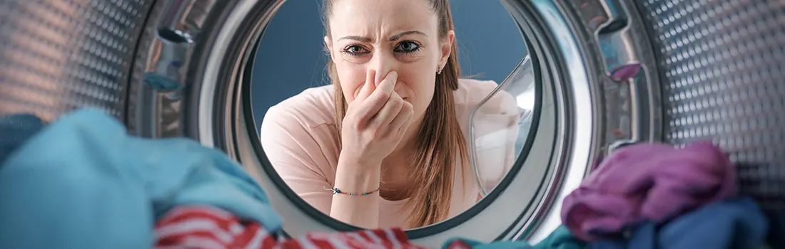 Een wasmachine gevuld met blauwe, rode en paarse was, gezien van binnenuit.