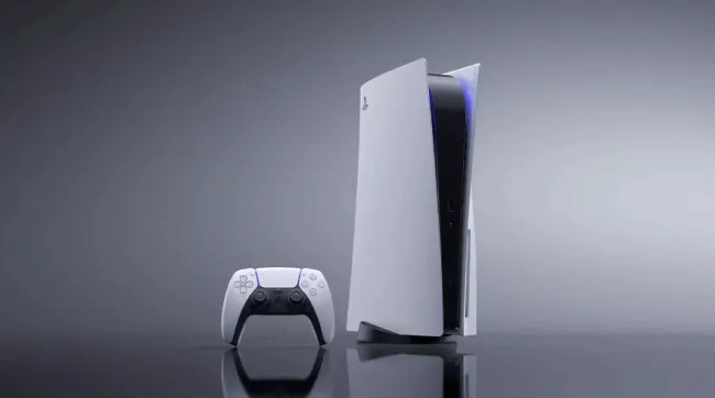 Une console de jeu blanche et une manette sont sur une surface brillante devant un fond gris dégradé.