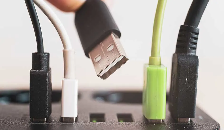 Zicht op een zwart apparaat met meerdere gekleurde USB-kabels (zwart, wit, groen) die zijn aangesloten, één kabel wordt ingeplugd.