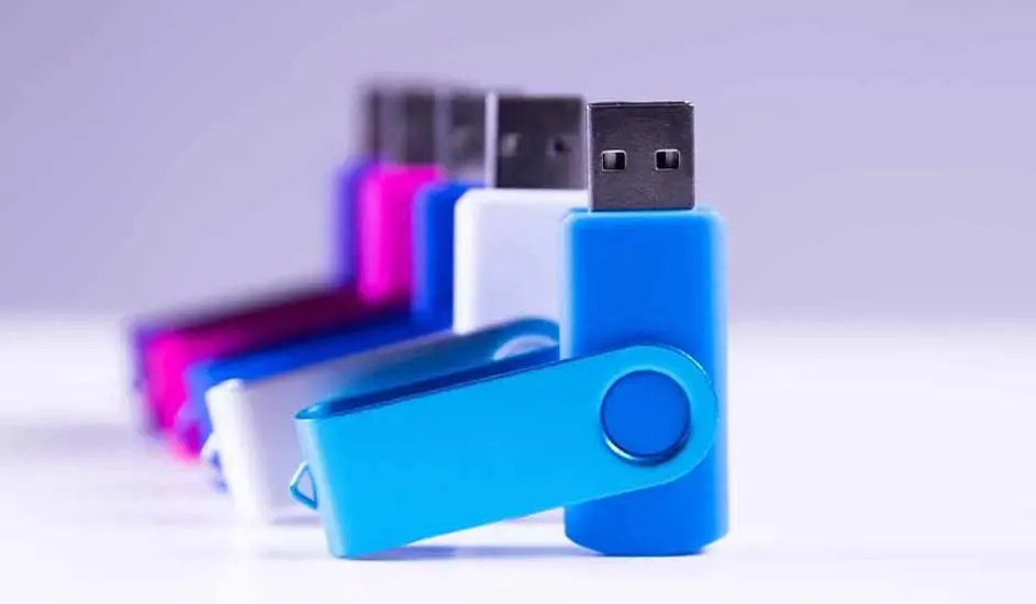 Rij van USB-sticks in blauw, wit en roze op een witte ondergrond. De metalen connectoren zijn zichtbaar aan de bovenkant.