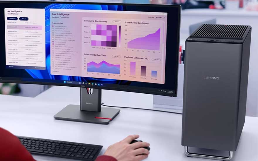 Een Lenovo-desktop staat naast een monitor met paarse grafieken en analyses, terwijl iemand met toetsenbord en muis werkt.