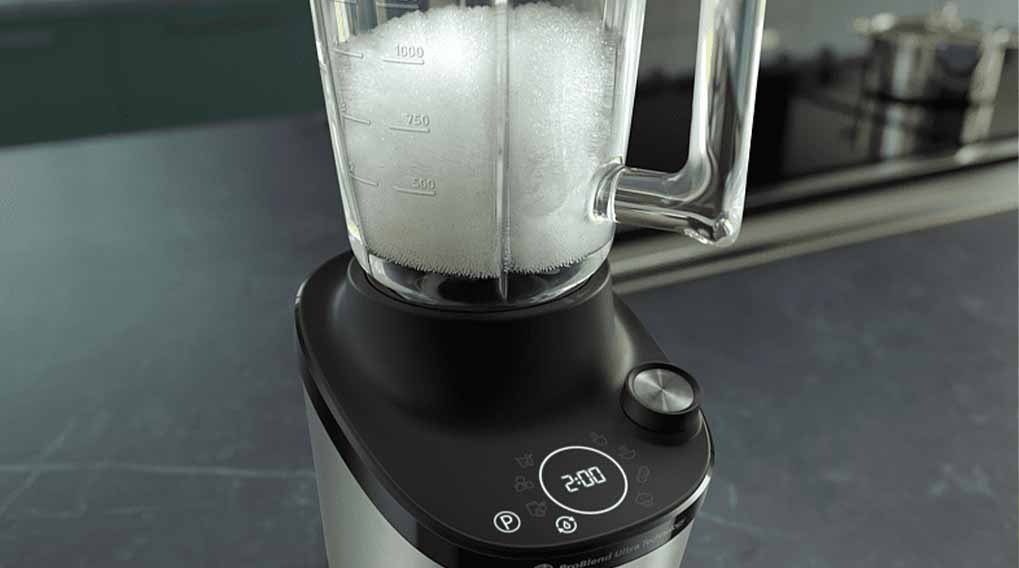Een blender met een glazen kan gevuld met een witte substantie, staat op een zwart en zilveren basis. De timer toont 2:00.