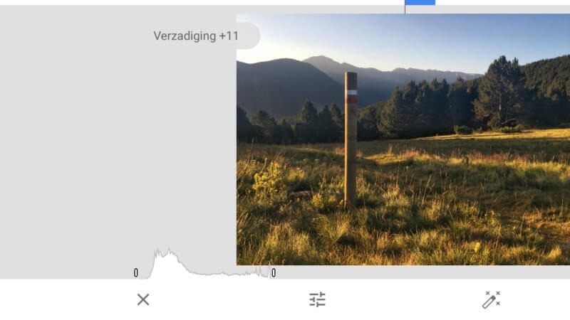 Image d'un paysage avec un poteau en bois au premier plan, de l'herbe et des montagnes en arrière-plan.