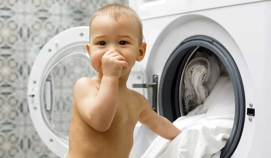 Een wasmachine met een open deur staat op een betegelde vloer. Er zit witte was in de trommel.