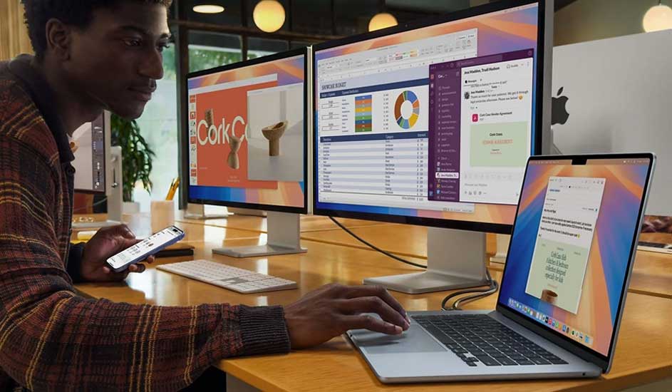 Een bureau met een laptop, toetsenbord, smartphone en twee monitoren waarop grafieken en documenten worden weergegeven.
