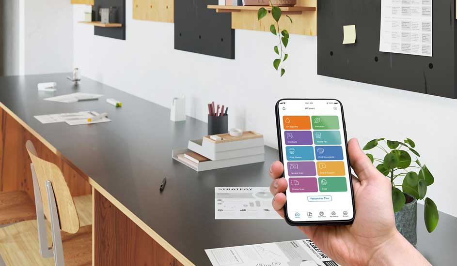 Een kantoorruimte met een bureau, een telefoon met een app, een plant en kantoorbenodigdheden.