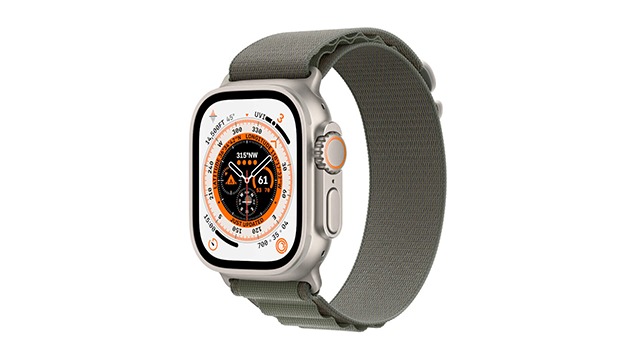 Montre intelligente grise avec un bracelet gris. L'écran affiche une face de montre complexe. Fond blanc.