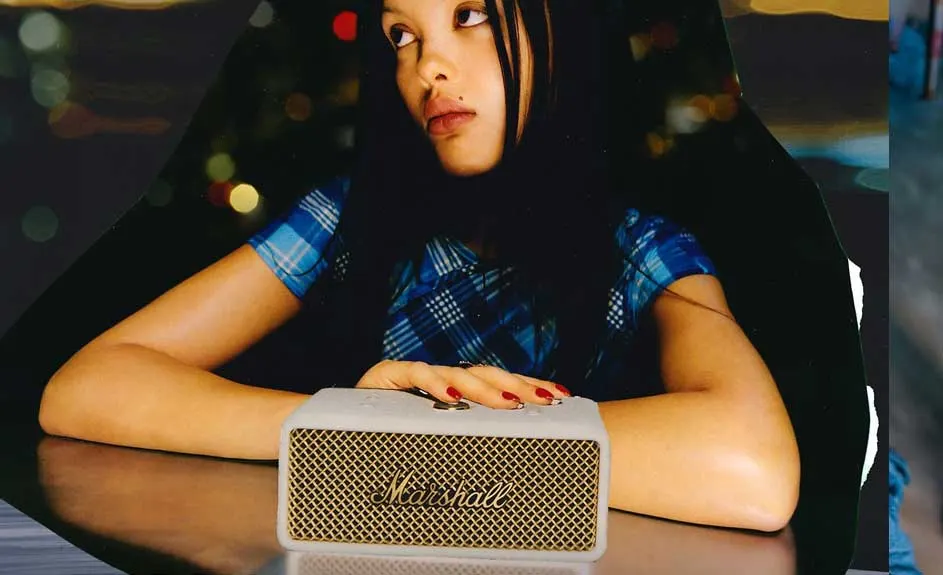 Een witte Marshall-luidspreker op een tafel met een gouden rooster. Op de achtergrond is een donkere en vage achtergrond.