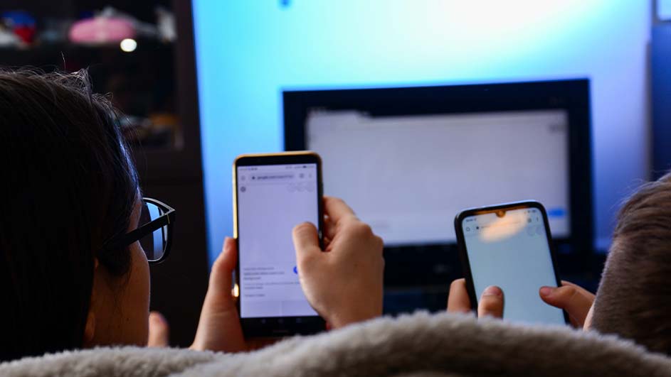 Deux téléphones allumés sont tenus devant un écran de télévision bleu clair.