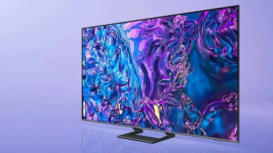 Een moderne Samsung-tv staat op een paarse achtergrond en toont een abstracte afbeelding met glanzende blauwe en paarse effecten op het scherm.