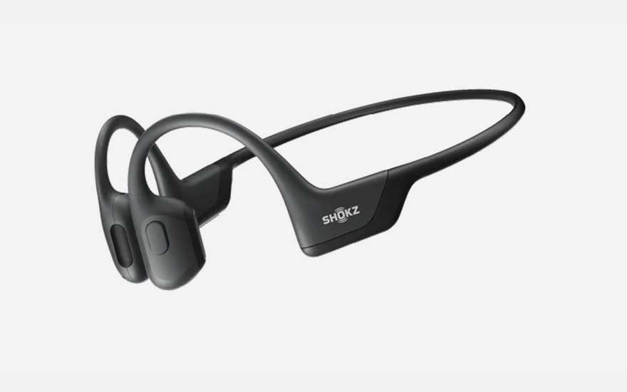 A sidewalk view features a brown jacket and white headphones, with a silver truck visible in the background on a street.