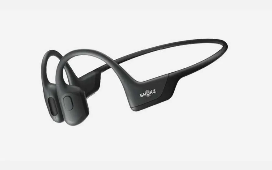 A sidewalk view features a brown jacket and white headphones, with a silver truck visible in the background on a street.