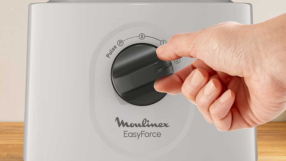 Een witte Moulinex EasyForce blender met een hand die de zwarte knop naar stand 1 draait.